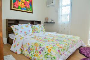 a bed with a floral comforter in a bedroom at MAILZ HAVEN BEAUTIFL 3BR MODERN APRT NEAR SM DOOR-C in Davao City
