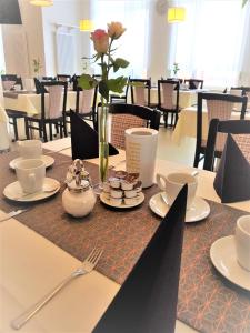 une table avec des assiettes et des tasses et un vase avec des fleurs dans l'établissement Hotel Weissach Am Neuenbühl, à Weissach