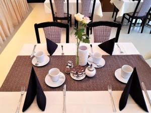 une table avec des assiettes et des tasses et un vase avec des fleurs dans l'établissement Hotel Weissach Am Neuenbühl, à Weissach