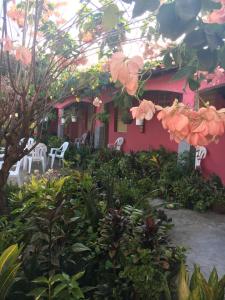 una casa rosa con sedie e fiori bianchi di Algodoal Bela Mar Pousada ad Algodoal