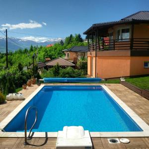a large blue swimming pool in front of a house at Vila Sani in Sarajevo