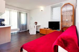 un soggiorno con divano rosso e TV di Keser Apartments a Rovigno (Rovinj)