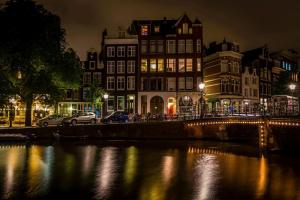 a bridge over a river with buildings at night at Canal View B&B Amsterdam in Amsterdam