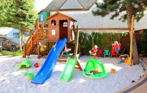 a playground with a slide and play equipment in the sand at Villa Róża pokoje & apartamenty in Łeba