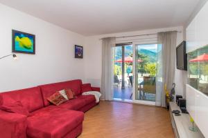 - un salon avec un canapé rouge et une porte coulissante en verre dans l'établissement Apartment Dalia - Cremia, à Cremia