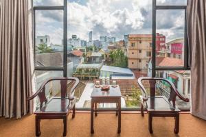 uma mesa e duas cadeiras em frente a uma grande janela em Amona Hotel em Hue