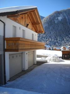 un edificio con due porte garage e un tetto in legno di App. Daverda Walter Strada al Plan Dessora 26 a San Vigilio Di Marebbe