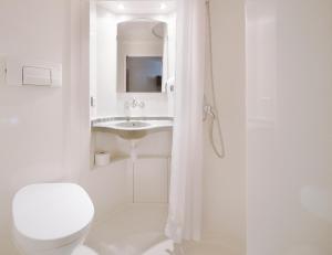 a white bathroom with a toilet and a sink at Premiere Classe Varsovie/Warszawa in Warsaw