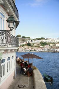 a group of people sitting under an umbrella on a pier at 1872 River House by Olivia in Porto