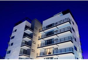 un edificio alto de color blanco con balcones encima en Ventura Apartments en Celaya