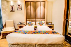 um quarto de hotel com uma cama grande e uma cadeira em FabHotel Prime V Hazratganj em Lucknow