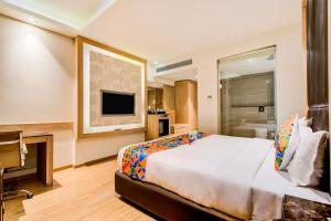 een hotelkamer met een groot bed en een televisie bij FabHotel Prime V Hazratganj in Lucknow