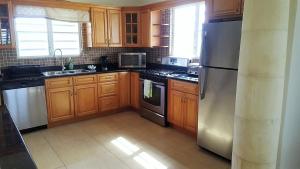 a kitchen with wooden cabinets and a stainless steel refrigerator at White Sands Anguilla - Sea in Blowing Point Village