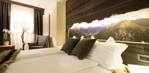 a bedroom with a white bed with a painting on the wall at Sport Hotel Majarè in Pozza di Fassa
