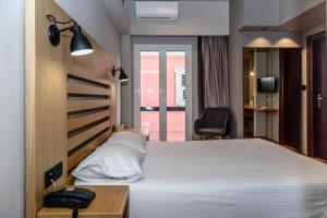 a bedroom with a large white bed and a chair at Agamemnon Hotel in Nafplio