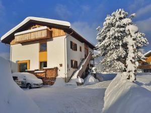 a snow covered house with a tree in front of it at Casa Shania in Unterwössen