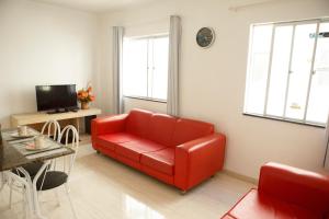 a living room with a red couch and a table at Apartamento 2 quartos in Laguna