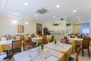 a restaurant with tables and chairs with yellow table cloth at Hotel Savana in Rimini
