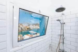 a window in a bathroom with a view of a city at Gorgona Traditional 2 in Karpathos Town +14 photos