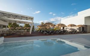 un complejo con piscina, mesas y sombrillas en Hotel Alto Lido en Funchal