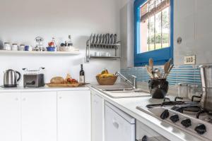 a white kitchen with a sink and a stove at Casa Casciu La collina sul mare in Costa Rei +19 photos