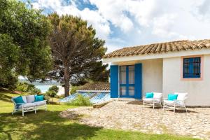 a house with blue and white chairs in the yard at Casa Casciu La collina sul mare in Costa Rei