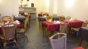 uma sala de jantar com mesas e cadeiras com toalhas de mesa vermelhas em Hôtel de Londres em Le Mont-Dore