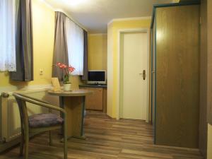 um quarto com uma mesa, uma cadeira e uma porta em Pension Ottendorf-Okrilla em Ottendorf-Okrilla
