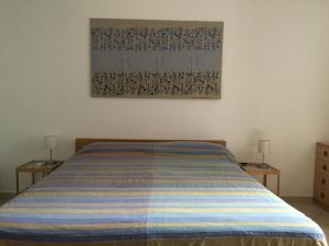 een slaapkamer met een bed met een gestreepte deken bij Casa sulla Spiaggia- Mortelle in Messina