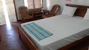 a bedroom with a large bed with two chairs at Sai Seashell Rest Inn Nilaveli in Trincomalee