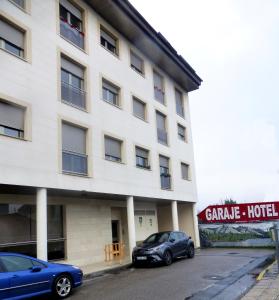 dos coches estacionados frente a un edificio en Hotel Villa de Cacabelos en Cacabelos