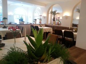 un comedor con mesas, sillas y plantas en Hotel Helena en Neu Wulmstorf