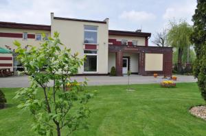 uma casa com um relvado verde em frente em Bankietowa Hotel & Restauracja em Ostrów Wielkopolski