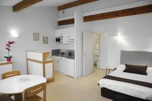 a bedroom with a bed and a table and a kitchen at Résidences Guerlin in Toulouse