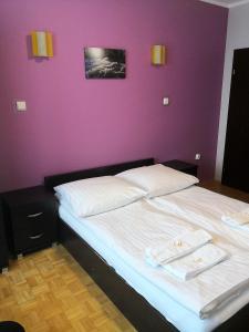 a bedroom with two beds and a purple wall at Leniwy Motyl in Rajcza