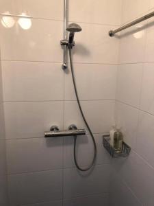 a shower with a hose in a white tiled bathroom at Canal View B&B Amsterdam in Amsterdam