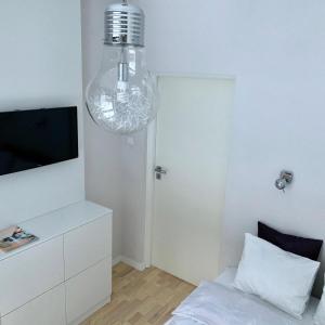 ワルシャワにあるAPARTELLO Modern Apartment - Wilanówのベッド、テレビ、シャンデリアが備わる客室です。