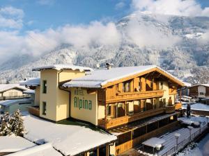 een gebouw in de sneeuw met een berg op de achtergrond bij Hotel Alpina in Ried im Zillertal