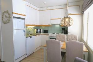 a kitchen with white cabinets and a table with chairs at Apartments Huili in Tahkovuori +40 photos