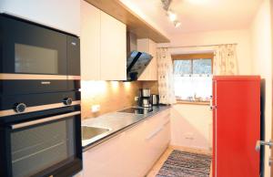 eine Küche mit einem roten Kühlschrank und einer Spüle in der Unterkunft Chalet Glemmtal - Haus Dorfblick in Viehhofen