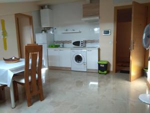 a kitchen with a washing machine and a table at Hostal Caminito in La Bañeza