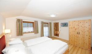 Schlafzimmer mit einem weißen Bett und Holzböden in der Unterkunft Chalet Glemmtal - Haus Dorfblick in Viehhofen