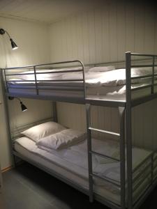 a room with three bunk beds with white pillows at Svinøya, hyggelig leilighet in Svolvær
