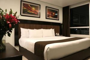 a bedroom with a large bed and a vase of flowers at Hotel & Suites PF in Mexico City