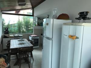 2 weiße Kühlschränke in einer Küche mit einem Tisch in der Unterkunft CASA AUGUSTA, Gravatá-PE in Gravatá