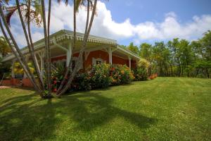 una casa con un patio de césped y una casa con flores en Villa avec piscine et vue mer (MQRO08), en Le Robert