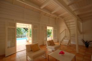 ein Wohnzimmer mit einer Treppe, Stühlen und einem Tisch in der Unterkunft Villa avec piscine au Cap Est (MQFR35) in Le François