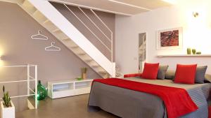 a bedroom with a bed with red pillows and a staircase at TrinaSicula Ragusa Ibla in Ragusa