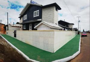 a house with a retaining wall and a green lawn at Pousada Boa Vista in São Joaquim