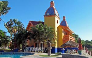 a building with a clock tower next to a swimming pool at Canadian Resort Vallarta in Bucerías